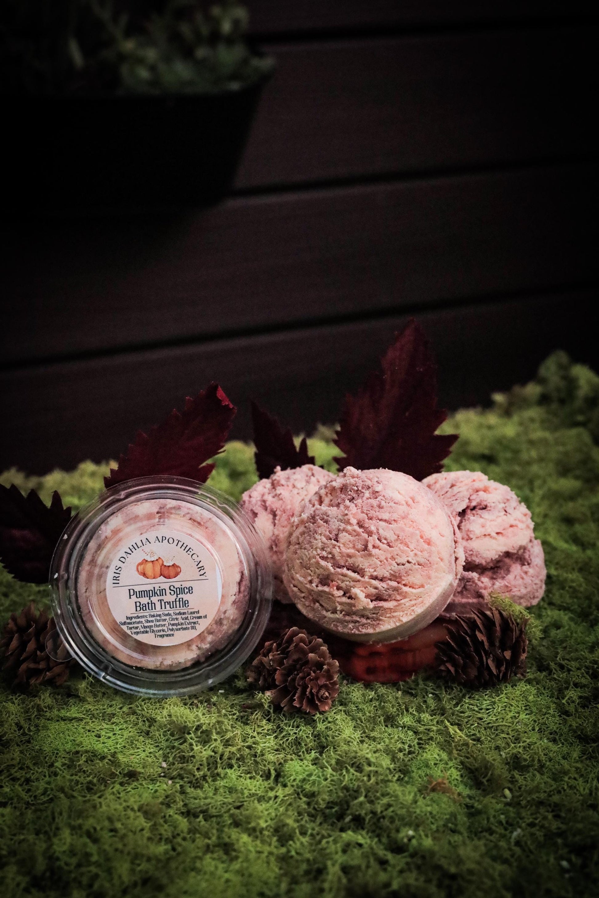 Handcrafted Pumpkin Spice Bath Truffle from Iris Dahlia Apothecary, styled in a scoop-like shape and displayed in an autumn-inspired setting with pinecones and moss.