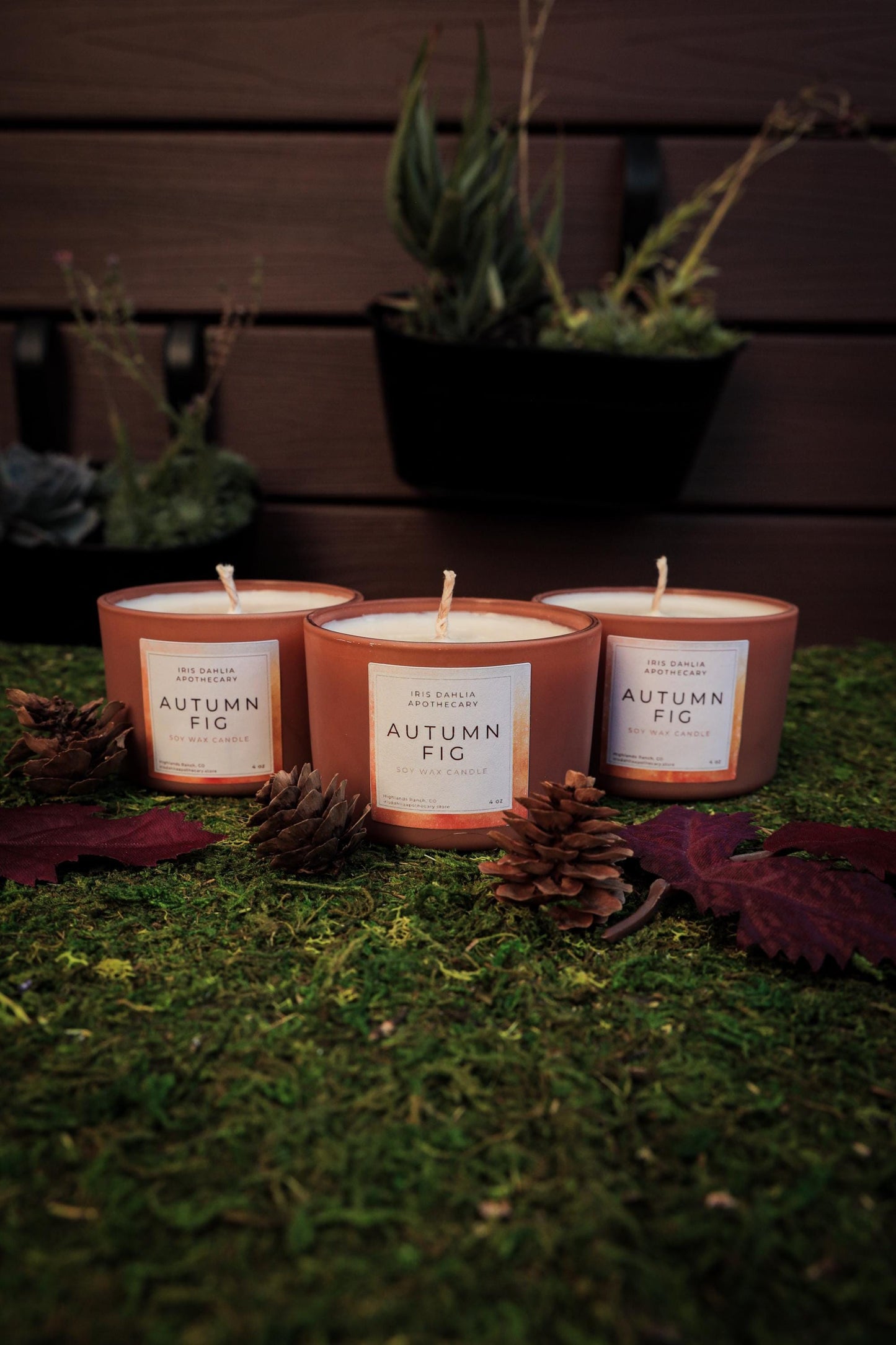 three candles sitting on top of a lush green field